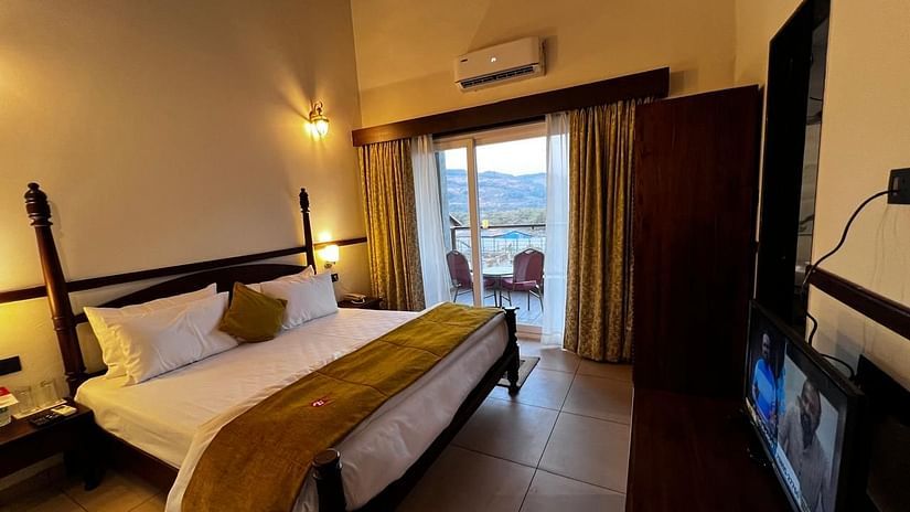 Royal Suite room featuring a large bed with plush bedding and a wide window at Mastiff Grand La Villae Resort, Lonavala